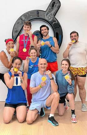 Olympians Nick Mead and Alex Karwoski, back row center, hold up gold medal sugar cookies baked by Aurore Thurstans of West Milford. Mead won a gold medal in rowing at the recent Summer Games in Paris. He and Karwoski, who competed in the 2016 Olympics, were leading a Peloton rowing class Aug. 18 in Bergen County. Both athletes work for Peloton. (Photos provided)