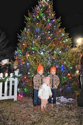 Children pose for photos in front of the tree.