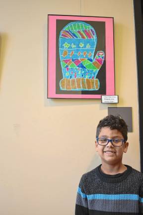 Greyson Lora, a first-grader at Apshawa Elementary School, in front of his ‘Mixed Media Mitten’ artwork.