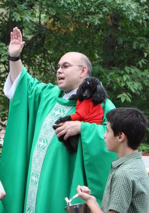 Fr. Michael gives a blessing to all the animals as he holds his own precious pet, Cupcake. Photo by Ginny Raue