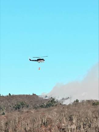 A New Jersey Forest Fire Service helicopter carries water to drop on the wildfires. (Photo by Denise von Wilke)