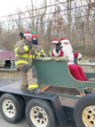 Santa and his helpers ride in a sleigh pulled by members of Greenwood Forest Volunteer Fire Company 3 as they travel through the Hewitt section of West Milford on Sunday, Dec. 18.