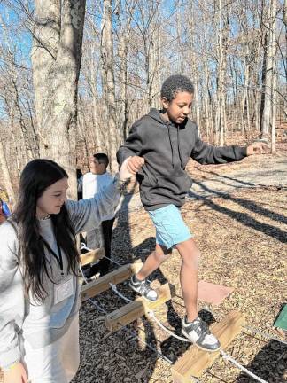 Jill’s House volunteer Gracie Almaleh helps a camper navigate the low rope obstacle course. (Photo provided)