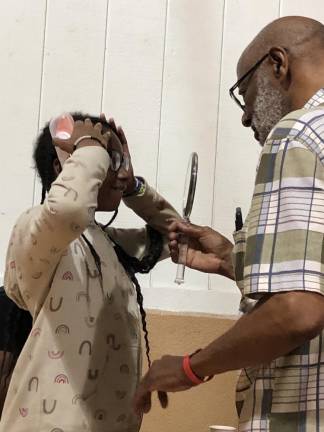 Optician Floyd Patterson of Vauxhall holds up a mirror for Haile Thomas to see herself wearing new glasses.