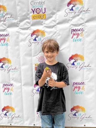 A boy holds a frog at the family day event. Sensory Garden and Play is a nature-based program that caters to children of different ages. It emphasizes hands-on exploration and discovery.