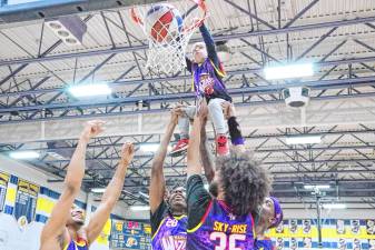 Several Harlem Wizards help Owen Magath, 4, of Jefferson dunk the ball to score the final point of a fundraising game Feb. 7 at Jefferson Township High School. (Photo by George Leroy Hunter)