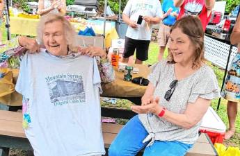 Judy Dorph-Ocello, right, Mountain Springs treasurer and owner of Stonehill Estates Kennel, presents Ellen Foster, 96, with an ‘Original cabin girl’ T-shirt at the Mountain Springs centennial celebration July 20. (Photo provided)