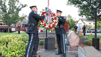 Two West Milford police officers place a wreath by the 9/11 Monument in front of the municipal building during a memorial ceremony Wednesday evening, Sept. 11. (Photos by Kathy Shwiff)