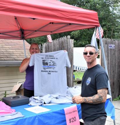 Brenda Lewin, a cousin of the late Peter Kamper Jr., sells a commemorative T-shirt to a rider.