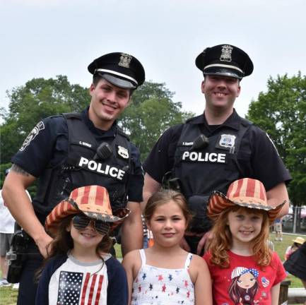 Greenwood Lake police Officers Cameron Gomas, left, and Kevin Bonkowski pose with girls decked out in red, white and blue for the parade.