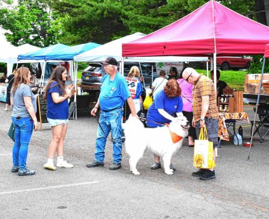 John Coco of Top of the Mountain Honey Bee Farm in Wantage, the vendor who has been with the West Milford market the longest time, greets customers with his dog. (Photos by Fred Ashplant)