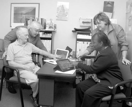 John Duffy, seated left, and Elizabeth Mangham, right, who have aphasia, are outpatients at the St. Anthony Community Hospital Department of Speech Pathology. Volunteer Liz Daly, left, and speech pathologist Loretta Lenihan communicate with Duffy and Mangham with the help of speech-generating devices.