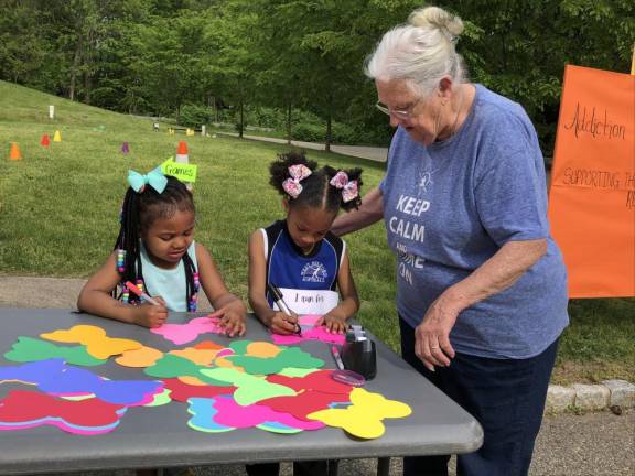 SF3 Kelly Williams of Hewitt helps her granddaughters write messages on the butterfly-shaped paper. Zuri Walker, 4, left, and her cousin Tayvionna Williams, 6, were running for Tayvionna’s mother, Jasmine Mann.