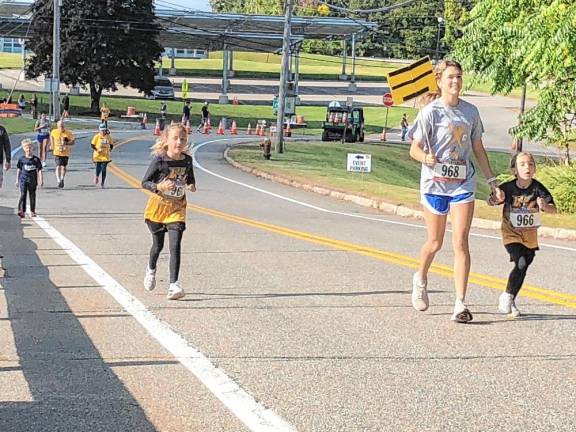 R. Leslie, 6, right, holds hands with Lola Novak, 16, as they run.