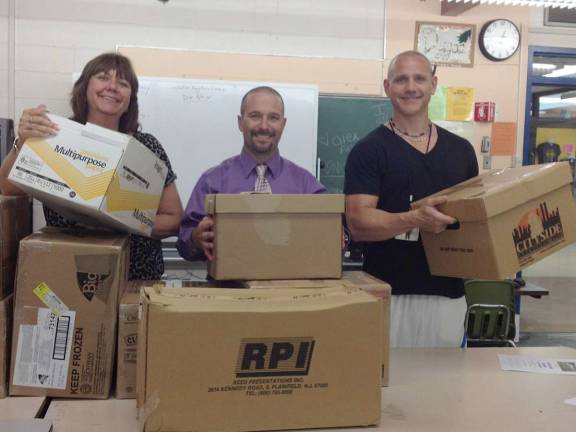 Macopin Middle School Principal Mary Reinhold, Assistant Principal Marc Citro and business teacher Richard Dygos are surrounded by the care packages they put together for soldiers in Afghanistan via Operation Thank You.