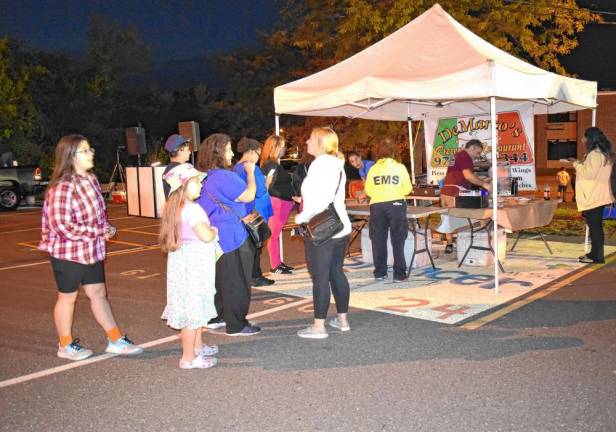 Residents line up for food at the DeMarco’s Pizzeria &amp; Restaurant table.