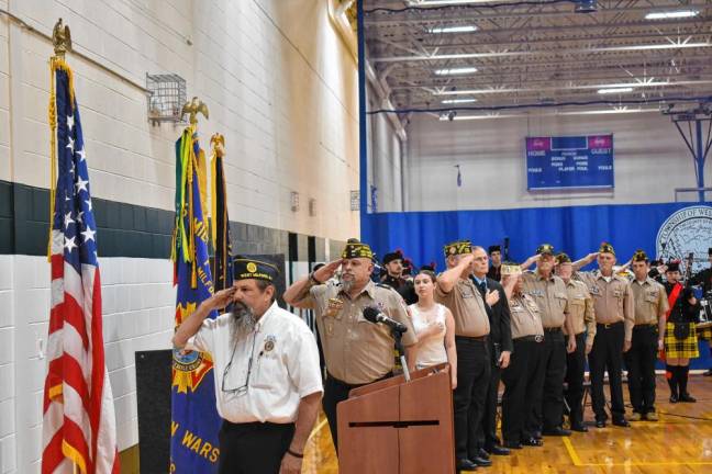 Veterans along with singer Gillian Rasp salute the colors.