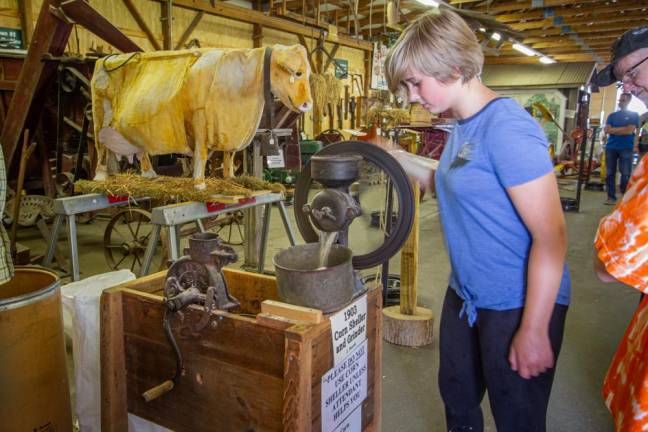 <b>In the museum, a fairgoer makes cornmeal using an antique corn sheller and grinder from 1903.</b>