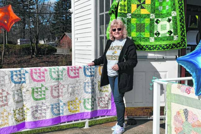 QT2 Helen Ryan stands by quilts on display outside the museum.