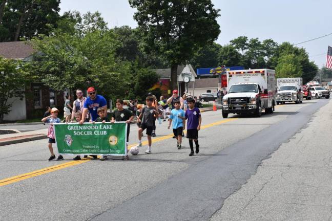 Members of the Greenwood Lake Soccer Club are followed by an ambulance and other emergency vehicles.