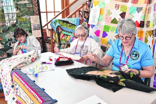 QT1 Shirley Ruggiero, center, of Hewitt binds a quilt Saturday, March 16 at the West Milford Museum. At left is Debbie Van Brunt of West Milford and at right is Meg Woznicki of Oak Ridge. They are members of the West Milford Heritage Quilters, which displayed members’ work on Worldwide Quilting Day. (Photo by Maria Kovic)