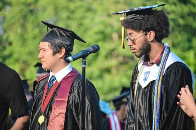 Graduates Aaron Reichert and Emilio McDonald prepare to sing the National Anthem.