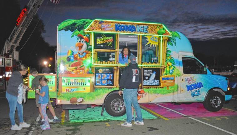 A woman helps a customer at the Kona Ice food truck.