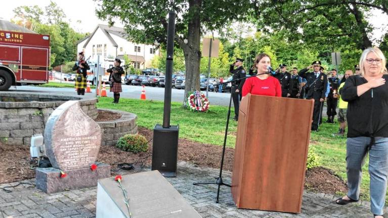 Gillian Rasp sings the National Anthem during the ceremony. At right is Mayor Michele Dale.