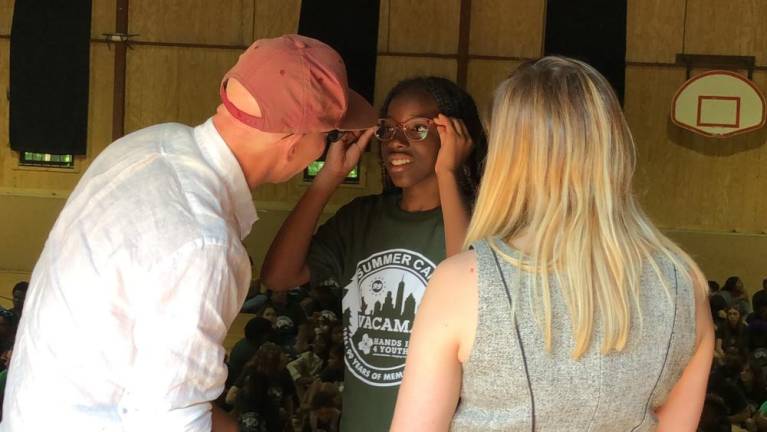 Paige Bonilla tries on a new pair of glasses Wednesday, July 26 at Camp Vacamas in West Milford. Helping her is John Jonas, co-president of Jonas Philanthropies. (Photos by Kathy Shwiff)