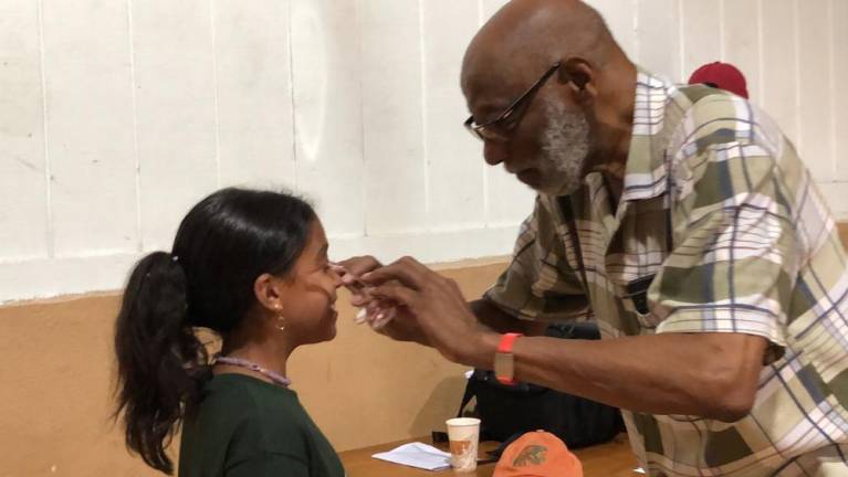 Optician Floyd Patterson helps fit new glasses on Jasayra Gonzalez.