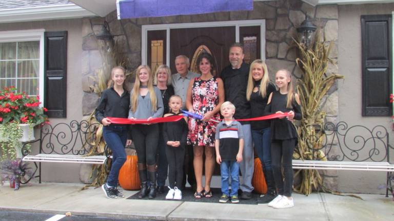 Mayor Bettina Bieri cuts the ceremonial ribbon for the Country Cottage Restaurant and Bar Monday. With the mayor are owners Steve and Tammy Witte and their children Amanda, Diana, Olivia, Julia, and Kyle and grandparents Earl and Gail Perritt. PHOTO BY ANN GENADER