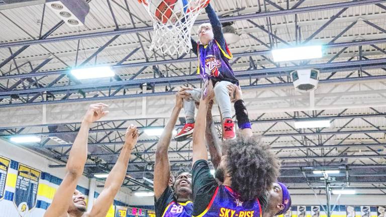 Several Harlem Wizards help Owen Magath, 4, of Jefferson dunk the ball to score the final point of a fundraising game Feb. 7 at Jefferson Township High School. (Photo by George Leroy Hunter)